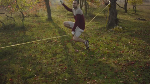 Caucasian man sets slackline between trees in the autumn forest. Stock-Footage 142304329
