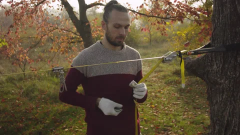 Caucasian man sets slackline between trees in the autumn forest. Stock-Footage 142306192