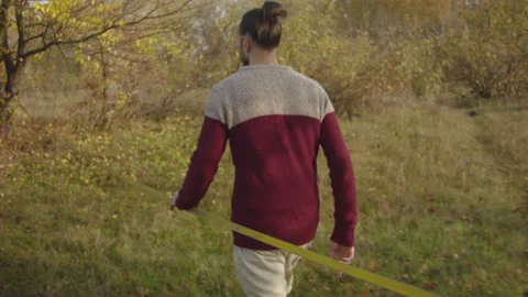 Caucasian man sets slackline between trees in the autumn forest. Stock-Footage 142306596