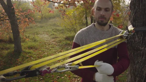 Caucasian man sets slackline between trees in the autumn forest. Stock-Footage 142311243