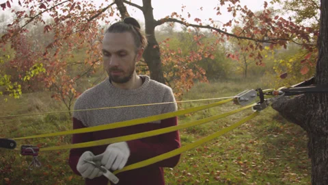 Caucasian man sets slackline between trees in the autumn forest. Stock-Footage 142311878
