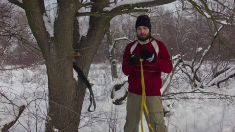 Caucasian man sets slackline between trees in the winter forest. 스톡 동영상 146961737