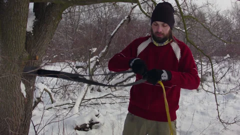 Caucasian man sets slackline between trees in the winter forest. 스톡 동영상 146964225