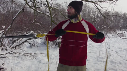Caucasian man sets slackline between trees in the winter forest. 스톡 동영상 146964246