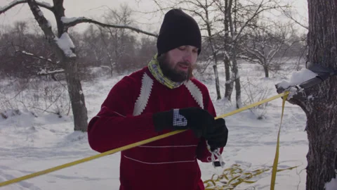 Caucasian man sets slackline between trees in the winter forest. 스톡 동영상 146970079