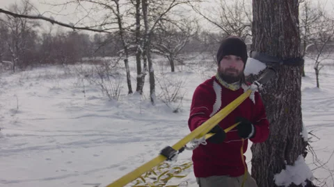 Caucasian man sets slackline between trees in the winter forest. 스톡 동영상 146970783