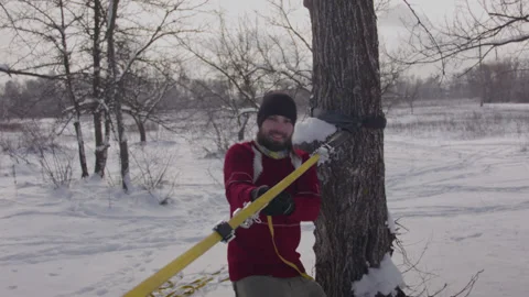 Caucasian man sets slackline between trees in the winter forest. 스톡 동영상 146970802