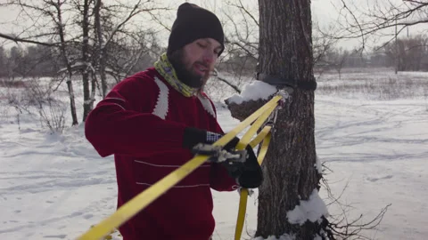 Caucasian man sets slackline between trees in the winter forest. 스톡 동영상 146975324