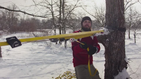 Caucasian man sets slackline between trees in the winter forest. 스톡 동영상 147148747