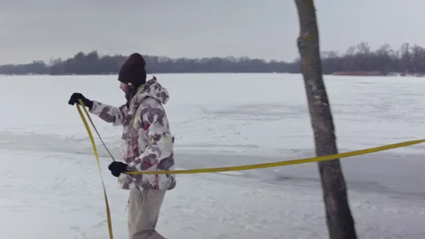 Caucasian man sets slackline between trees in the winter forest. Vídeo Stock 148085695
