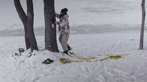 Caucasian man sets slackline between trees in the winter forest. 스톡 동영상 148097223