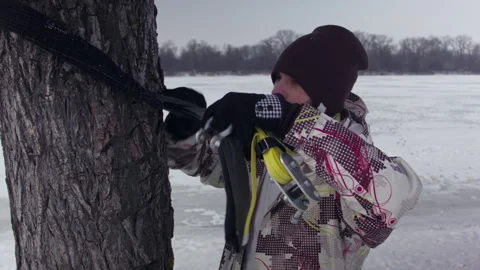 Caucasian man sets slackline between trees in the winter forest. 스톡 동영상 148097262