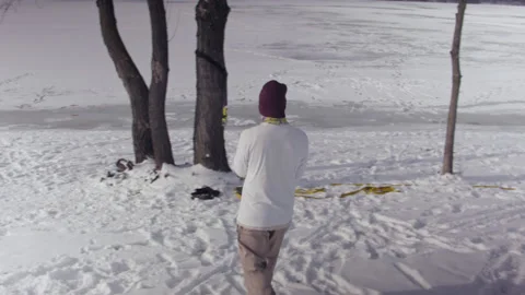 Caucasian man sets slackline between trees in the winter forest. 스톡 동영상 148097560