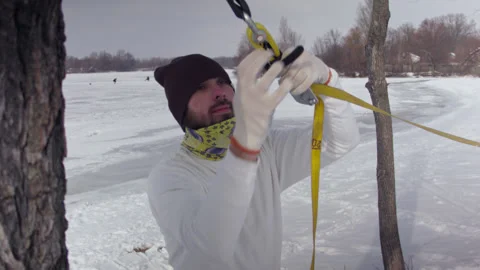 Caucasian man sets slackline between trees in the winter forest. 스톡 동영상 148115907