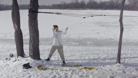 Caucasian man sets slackline between trees in the winter forest. Stock Footage 148164761