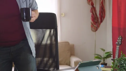A caucasian man sits down to work from home with a coffee - slow motion Stock Footage 129961853