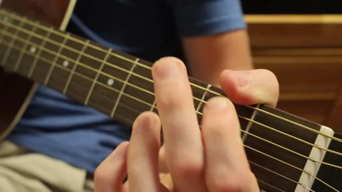 Caucasian man sitting down playing guitar with G chord and C chord Stock Footage 279909186
