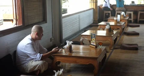 Caucasian man sitting in lotus position in cafe or restaurant setting 库存影片 282964382