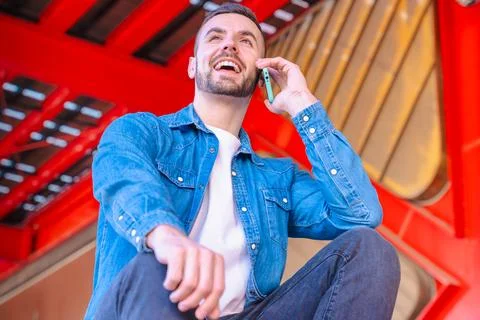 Caucasian man smiling while talking on smartphone in a modern urban environment Stock Photos
