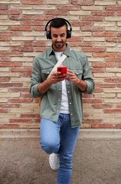 Caucasian man smiling while using phone to send online messages and listen music Stock Photos