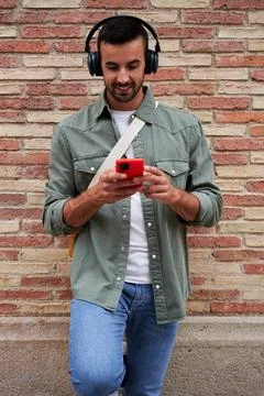 Caucasian man smiling while using phone to send online messages and listen music Stock Photos