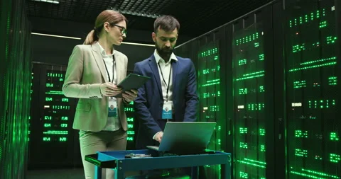 Caucasian man typing and coding on laptop computer and woman scrolling on tablet Stock Footage 137548735