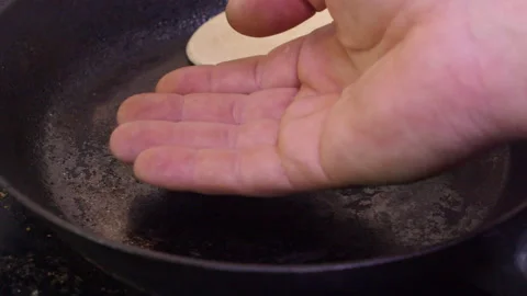 Caucasian man uses back of hand to test heat in cast iron pan on stove Video stock 263743704