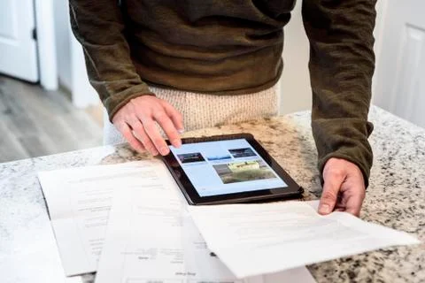 Caucasian man using digital tablet and holding paperwork 写真素材