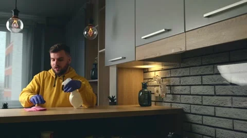 Caucasian man is using gloves and wipe while cleaning the house with special Stock Footage 147036448