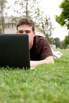 Caucasian man using laptop in grass 스톡 사진