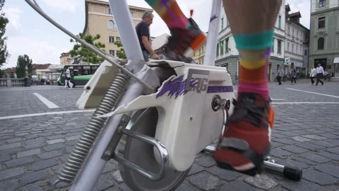 Caucasian man using old exercise bike in the middle of the town square close up  Stock Footage 121462106