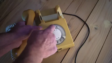 Caucasian man using an old, stationery ,rotary aged , yellow vintage telephone Stock-Footage 319889741