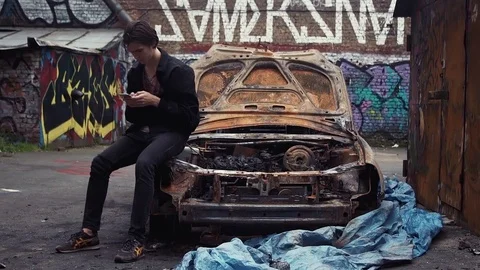 Caucasian man using smartphone sitting on fender of crashed car. Urban lifestyle Stock Footage 80008766