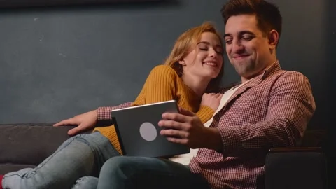 Caucasian man is using a tablet while his ginger woman with freckles is kissing Stock Footage 146582553