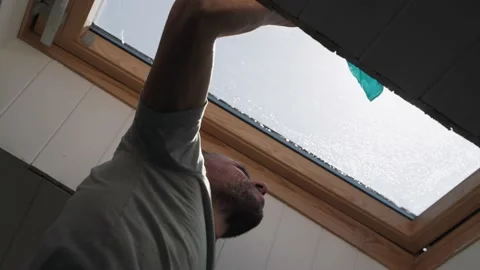 Caucasian man washes the attic window Bright sun illuminates the man in the Stock-Footage 153218766
