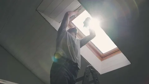 Caucasian man washes the attic window Bright sun illuminates the man in the Stock Footage 153219239