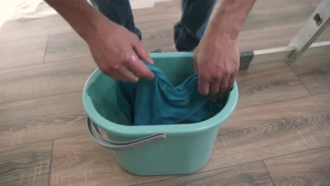 Caucasian man washes the attic window Man rinses a rag in a bucket of water Stock Footage 153220228