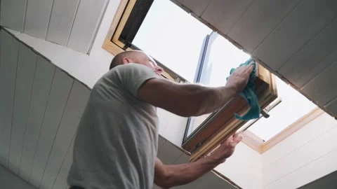 Caucasian man washes the attic window Bright sun illuminates the man in the Stock-Footage 153220667