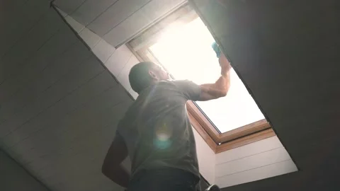 Caucasian man washes the attic window Bright sun illuminates the man in the Stock-Footage 153221179