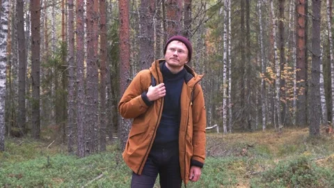 Caucasian man wearing backpack standing over forest background. A man with Stock Footage 164218316