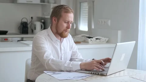 Caucasian man working remotely while sitting in the kitchen Stock Footage 140653998