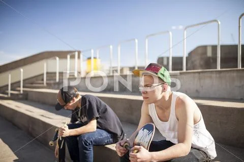 Caucasian Men With Skateboards Sitting On Steps