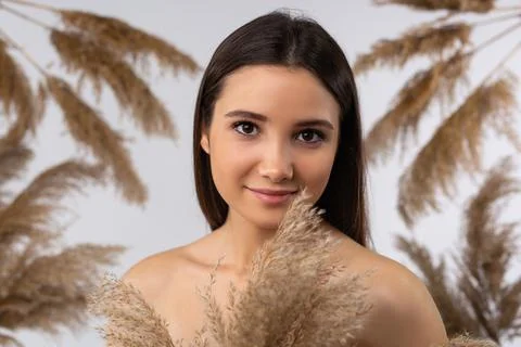 Caucasian model posing on gray background with dry pampas grass reeds. Minimal Stock Photos