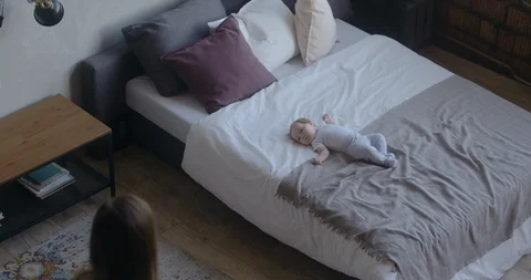 Caucasian mother brings balloon to her newborn baby laying on bed. RAW Graded fo Stock Footage