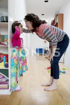 Caucasian mother measuring height of daughter on wall Stock Photos