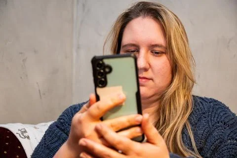 Caucasian mother using smartphone while relaxing at home in a cozy environmen Stock Photos