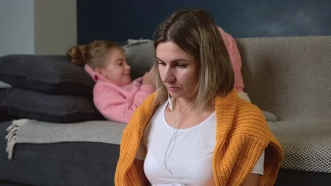Caucasian mother is working on the floor while her daughter on background lying Stock Footage 146953509