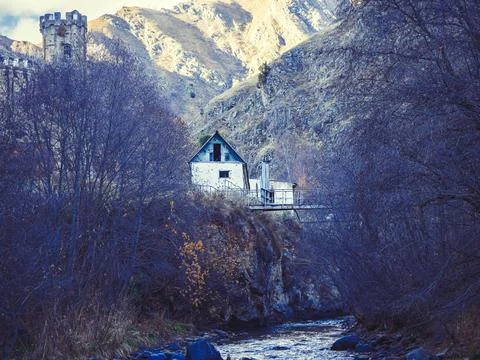 Caucasian mountain gorge with an old empty house and a rusting iron bridge over Stock Photos
