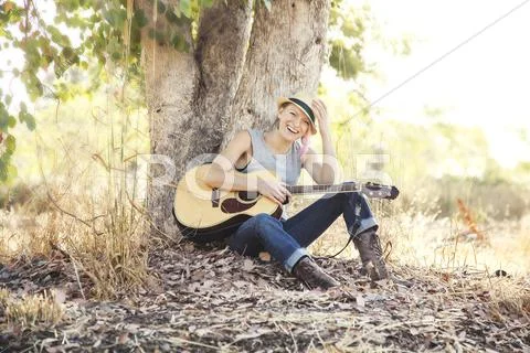 Caucasian Musician Holding Guitar Under Tree