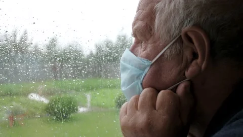 Caucasian Old Sadness Man In Protective Medical Mask Looks Out Window At Rain Stock Footage 134161898
